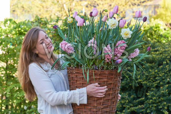 Young lady carrying basket with spring flowers Young lady carrying basket with spring flowers